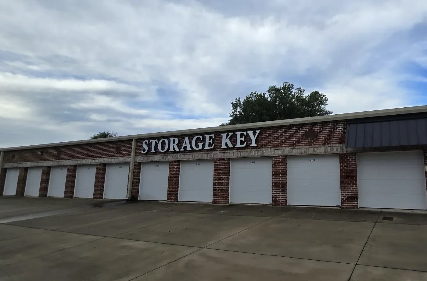 The brick storefront at The Storage Key on Grassdale Road in Cartersville, Georgia, with white roll-up doors numbered along the building.